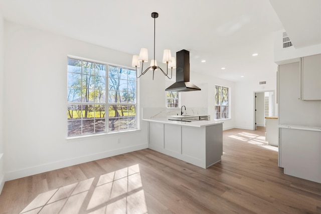 kitchen with island range hood, sink, white cabinets, hanging light fixtures, and kitchen peninsula