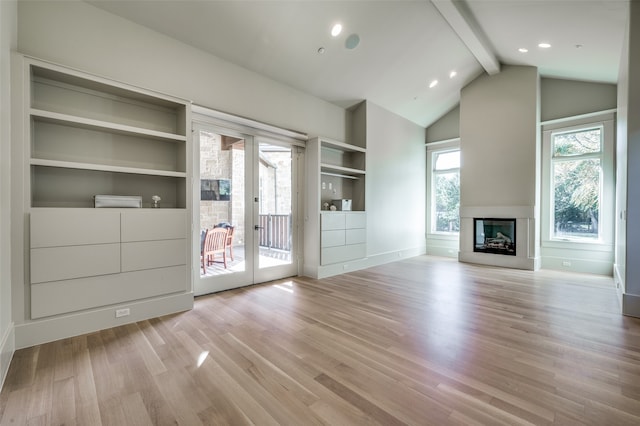 unfurnished living room with a wealth of natural light, lofted ceiling with beams, and light wood-type flooring