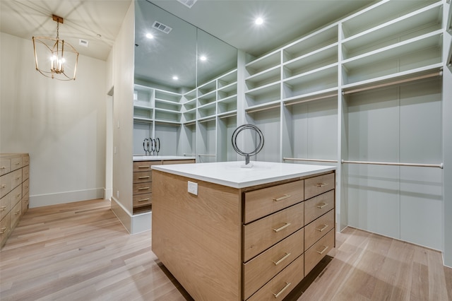 walk in closet with a chandelier and light hardwood / wood-style floors