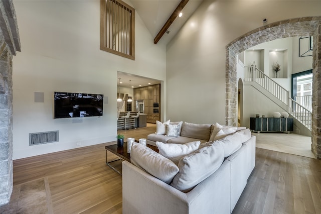 living room with hardwood / wood-style flooring, beam ceiling, and high vaulted ceiling