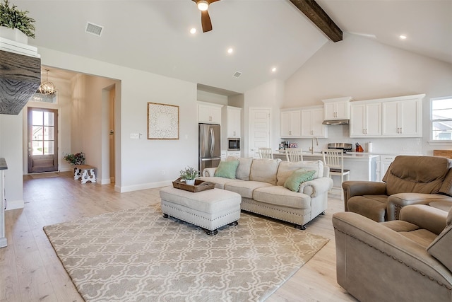 living room featuring ceiling fan with notable chandelier, sink, beam ceiling, high vaulted ceiling, and light hardwood / wood-style flooring