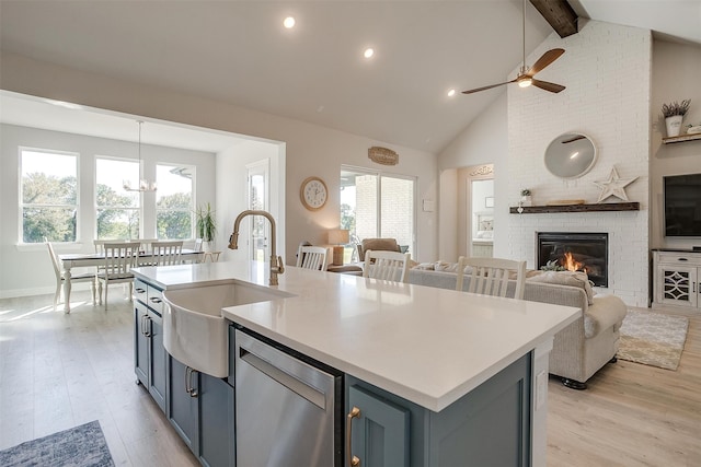 kitchen with a fireplace, a wealth of natural light, sink, and a center island with sink