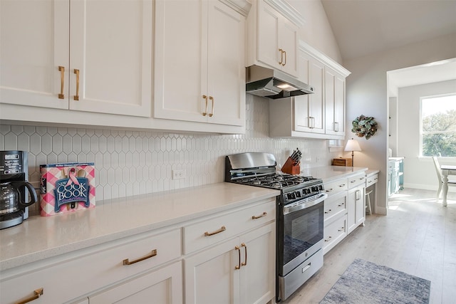 kitchen featuring gas range, white cabinetry, light hardwood / wood-style floors, vaulted ceiling, and decorative backsplash