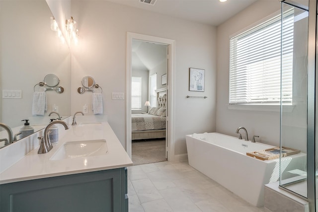 bathroom with a tub to relax in, vanity, and a healthy amount of sunlight