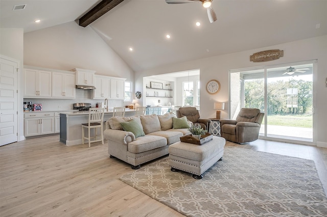 living room with light wood-type flooring, ceiling fan, sink, high vaulted ceiling, and beamed ceiling