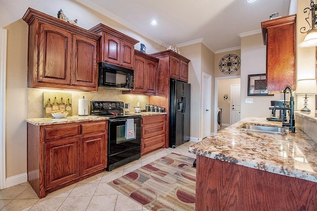 kitchen with light stone countertops, light tile patterned floors, black appliances, washer / clothes dryer, and sink