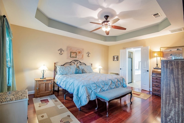 bedroom featuring dark wood-type flooring, a raised ceiling, and ceiling fan