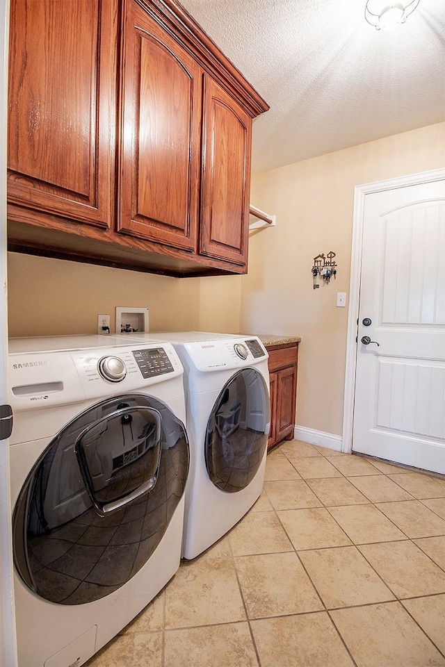 laundry room with washer and dryer, cabinets, a textured ceiling, and light tile patterned floors