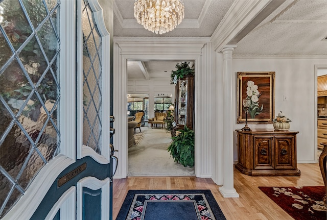 foyer featuring a chandelier, wood-type flooring, a textured ceiling, and decorative columns