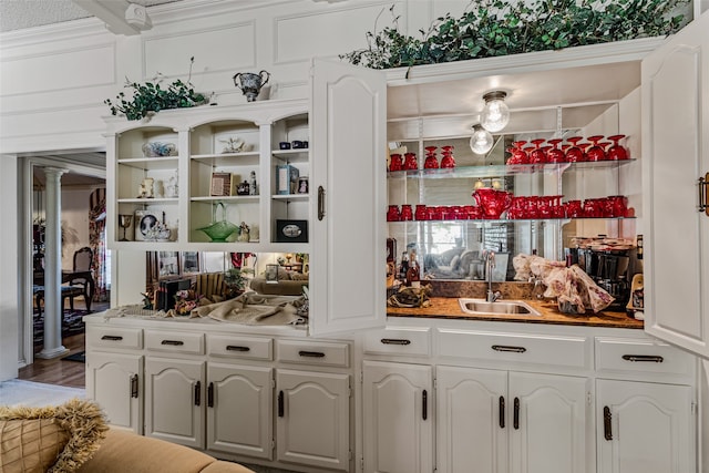 bar featuring hardwood / wood-style floors, white cabinetry, crown molding, and sink