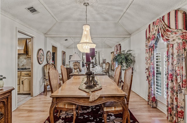 dining area featuring a textured ceiling, an inviting chandelier, light hardwood / wood-style flooring, and crown molding