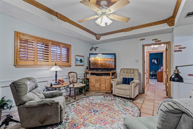 tiled living room featuring ceiling fan, a textured ceiling, and ornamental molding