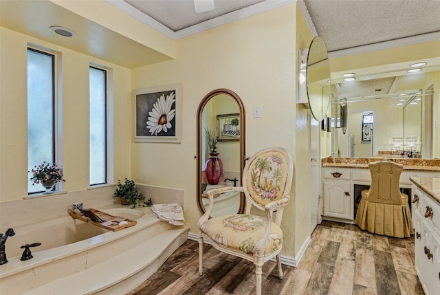 bathroom with a bath, hardwood / wood-style floors, a textured ceiling, vanity, and ornamental molding