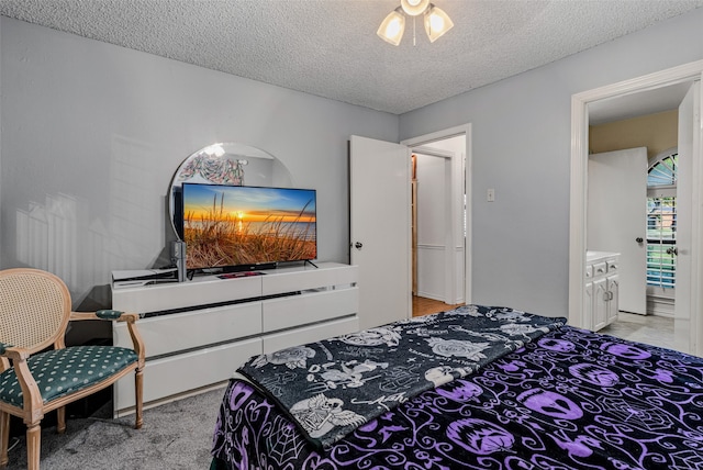 carpeted bedroom featuring ceiling fan, a textured ceiling, and connected bathroom