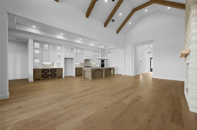 unfurnished living room with beam ceiling, sink, high vaulted ceiling, and hardwood / wood-style flooring