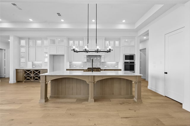 kitchen with a breakfast bar, a spacious island, hanging light fixtures, appliances with stainless steel finishes, and white cabinetry