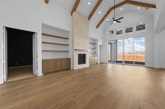 unfurnished living room featuring high vaulted ceiling, light hardwood / wood-style flooring, ceiling fan, a fireplace, and beamed ceiling