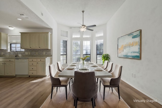 dining room featuring ceiling fan, sink, and light wood-type flooring