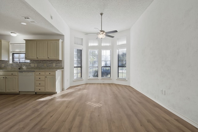 unfurnished living room with ceiling fan, light hardwood / wood-style floors, sink, and a textured ceiling