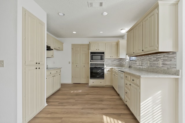 kitchen featuring light hardwood / wood-style flooring, black appliances, and cream cabinetry