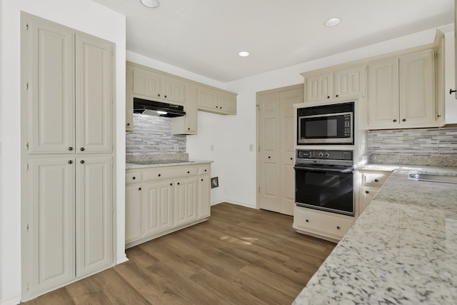 kitchen featuring cream cabinets, tasteful backsplash, light hardwood / wood-style flooring, and black appliances