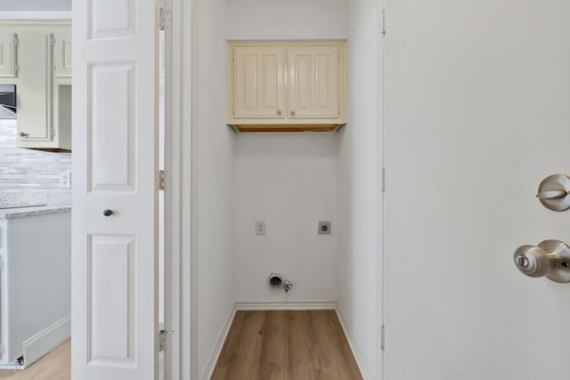 washroom featuring electric dryer hookup, light hardwood / wood-style flooring, and cabinets