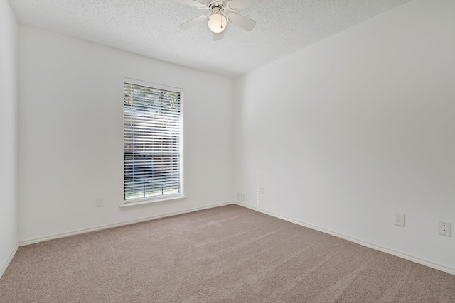 carpeted empty room with ceiling fan and a textured ceiling