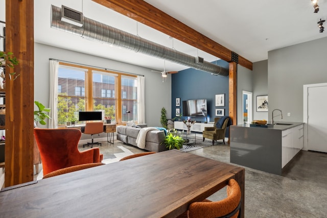 dining area featuring beam ceiling, concrete floors, and sink