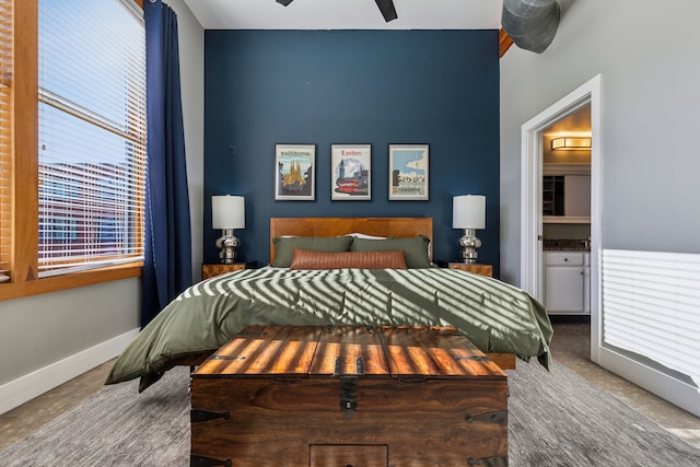 bedroom with concrete floors, ensuite bathroom, and ceiling fan