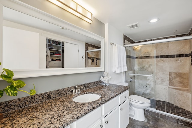 bathroom with a shower with door, vanity, and toilet