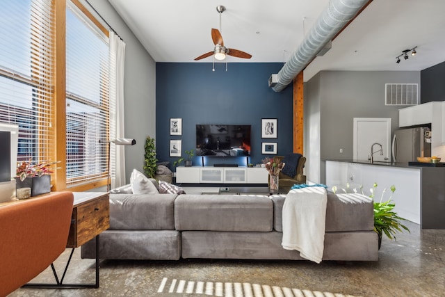 living room featuring ceiling fan, sink, and concrete floors