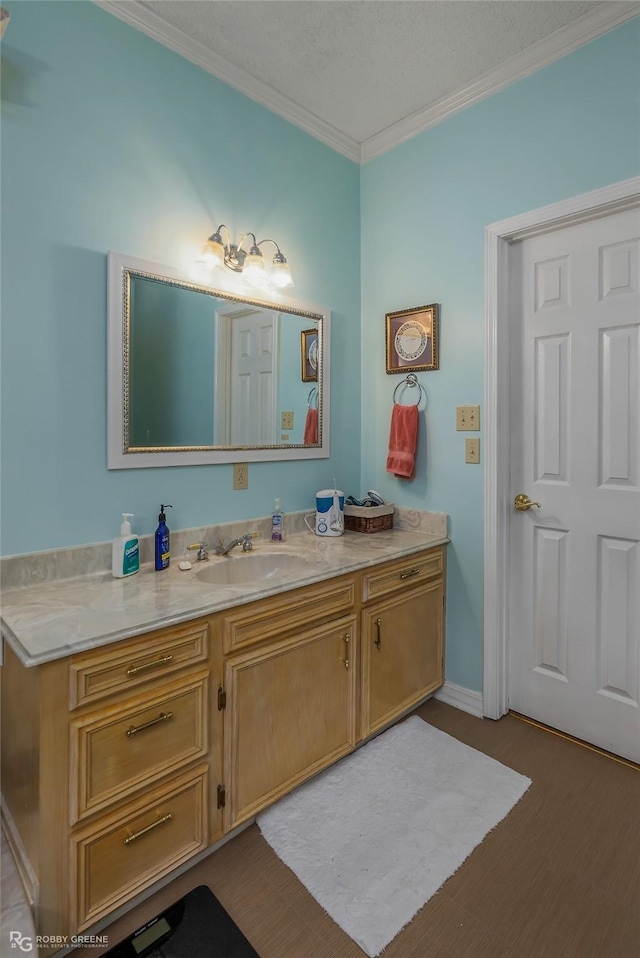 bathroom featuring wood-type flooring, vanity, a textured ceiling, and crown molding