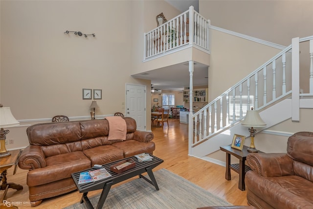 living room featuring hardwood / wood-style flooring, ceiling fan, and a towering ceiling