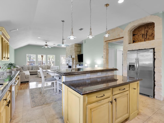 kitchen featuring stainless steel appliances, ceiling fan, decorative light fixtures, a fireplace, and a kitchen island