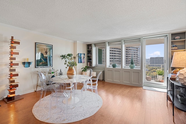 dining area with light hardwood / wood-style flooring, a textured ceiling, and ornamental molding