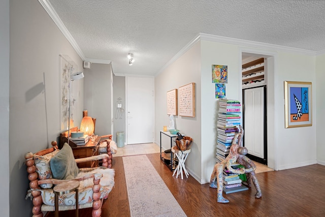 living area with a textured ceiling, light wood-type flooring, and ornamental molding