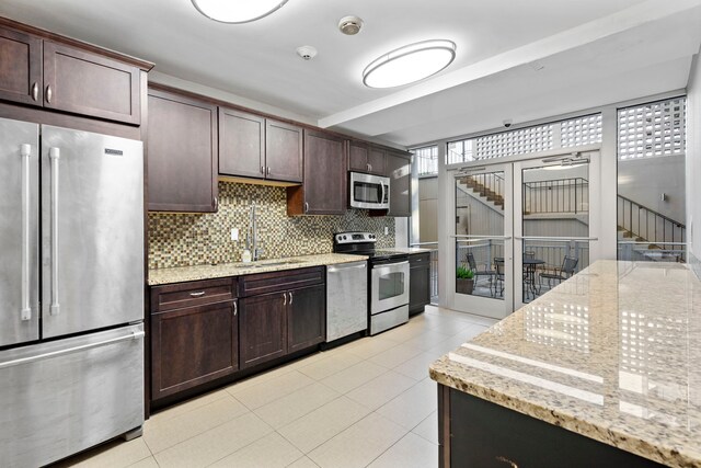 kitchen with light stone countertops, sink, dark brown cabinets, and appliances with stainless steel finishes