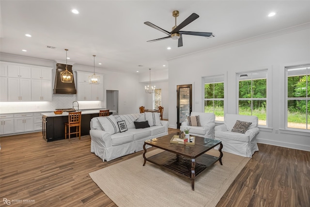 living room with ceiling fan with notable chandelier, dark hardwood / wood-style flooring, ornamental molding, and sink