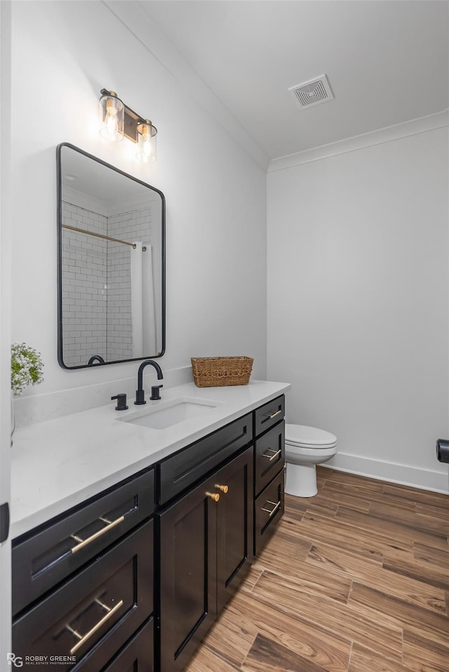 bathroom featuring walk in shower, crown molding, hardwood / wood-style floors, toilet, and vanity