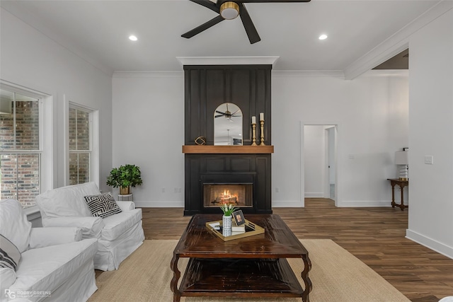 living room featuring hardwood / wood-style floors, ceiling fan, crown molding, and a fireplace