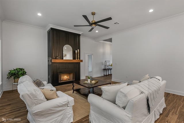 living room with crown molding, ceiling fan, and dark wood-type flooring