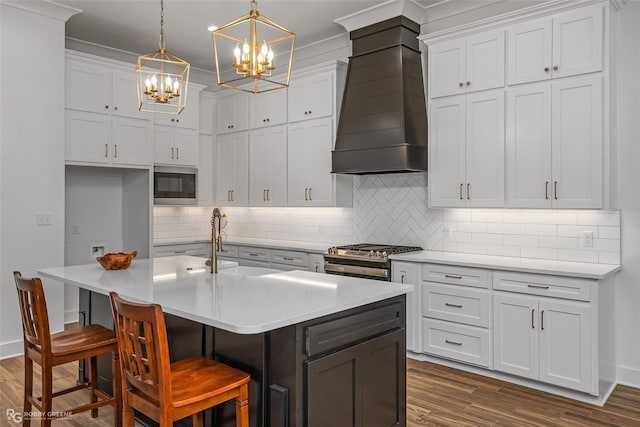 kitchen featuring custom exhaust hood, stainless steel appliances, a kitchen island with sink, pendant lighting, and dark hardwood / wood-style floors