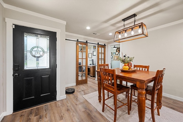 dining area featuring hardwood / wood-style flooring, a barn door, and crown molding