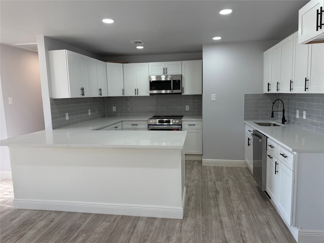 kitchen featuring kitchen peninsula, sink, white cabinets, and stainless steel appliances