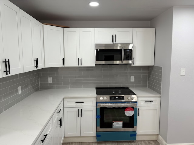 kitchen with decorative backsplash, light stone countertops, white cabinetry, and stainless steel appliances