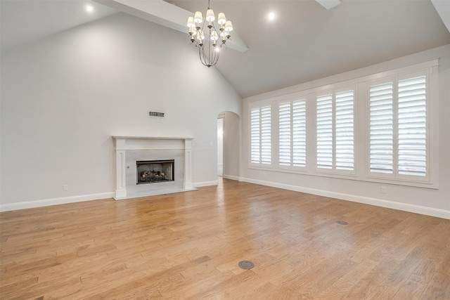 unfurnished living room featuring an inviting chandelier, a premium fireplace, high vaulted ceiling, and light hardwood / wood-style flooring