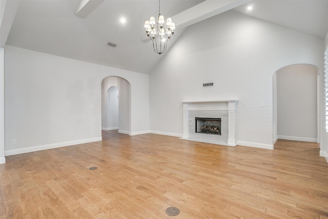 unfurnished living room featuring light wood-type flooring, high vaulted ceiling, and an inviting chandelier