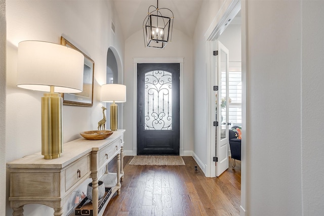 foyer entrance with an inviting chandelier, hardwood / wood-style flooring, and vaulted ceiling