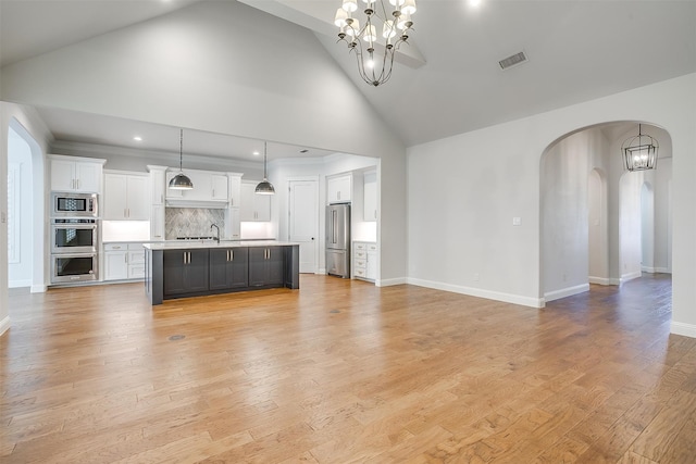 unfurnished living room featuring sink, light hardwood / wood-style flooring, high vaulted ceiling, and a notable chandelier