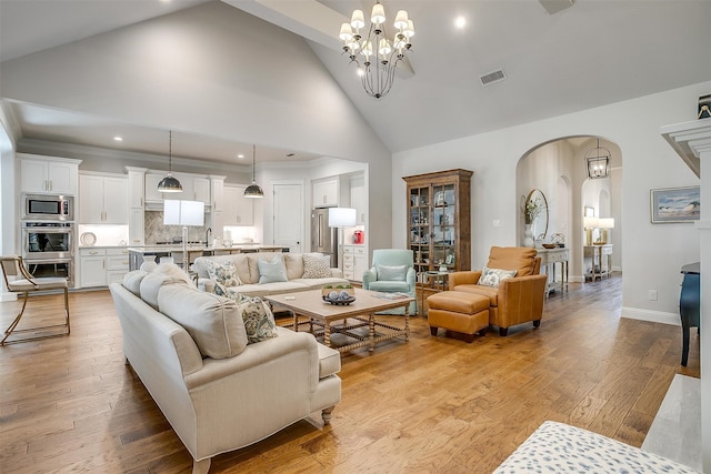 living room featuring an inviting chandelier, high vaulted ceiling, and light wood-type flooring